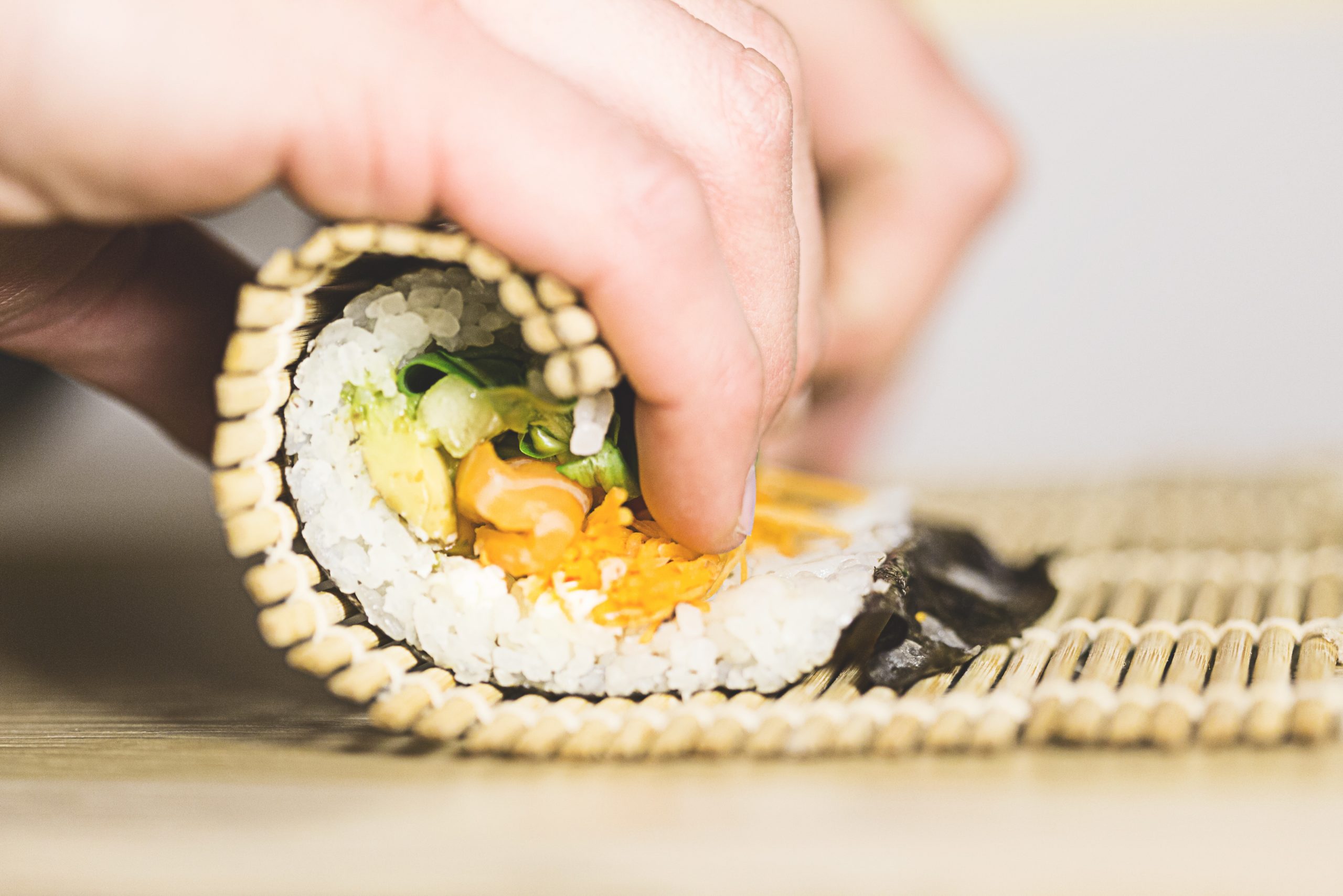 Hands rolling a sushi roll